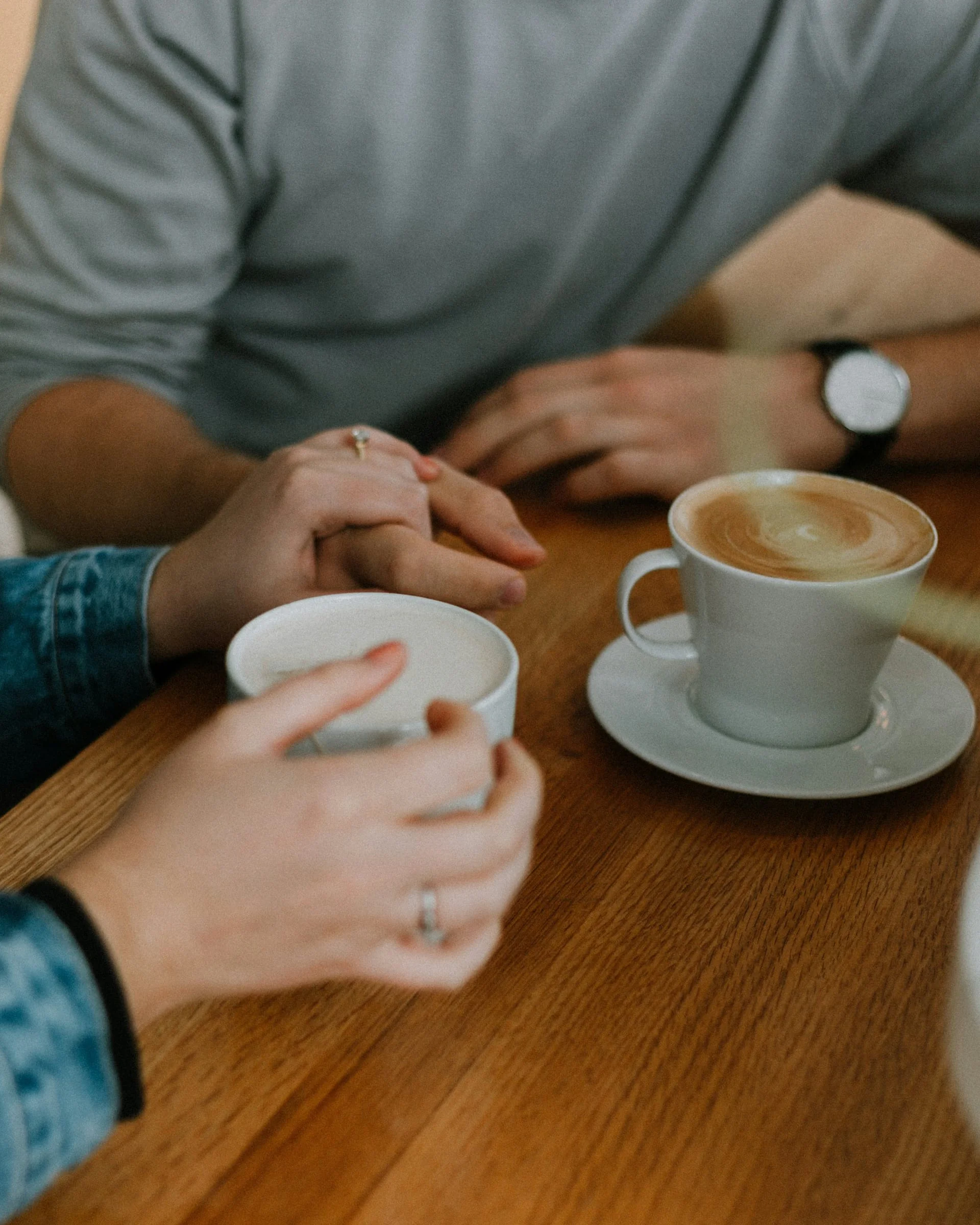 Twee mensen in gesprek aan een houten tafel, met een koffie tussen hen in