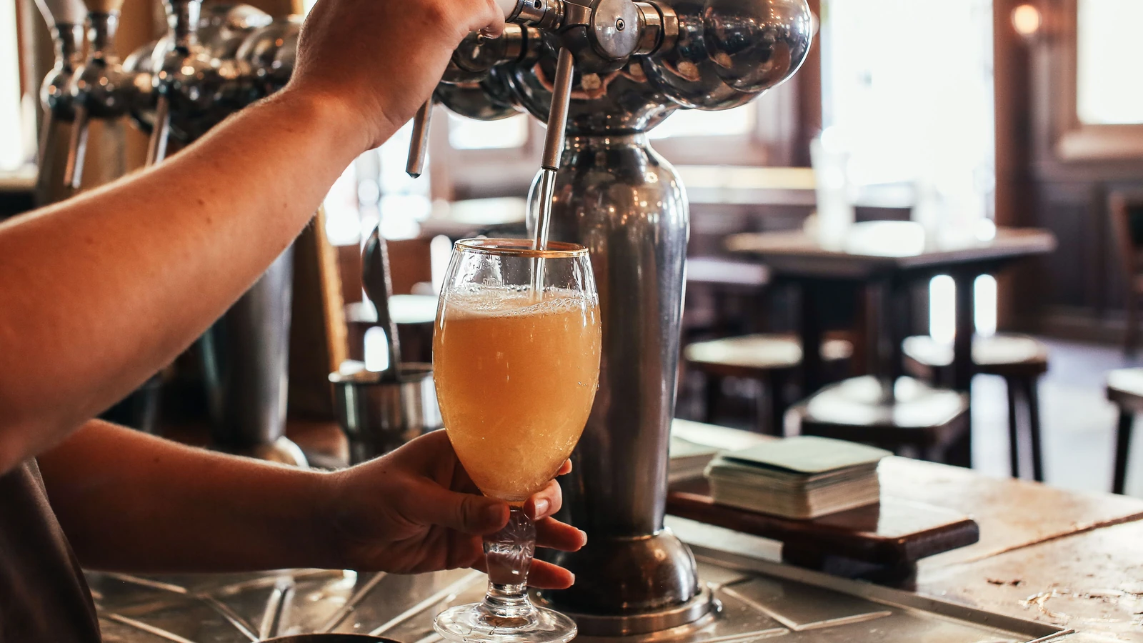 Bartender die een glas bier tapt aan de toog van een café