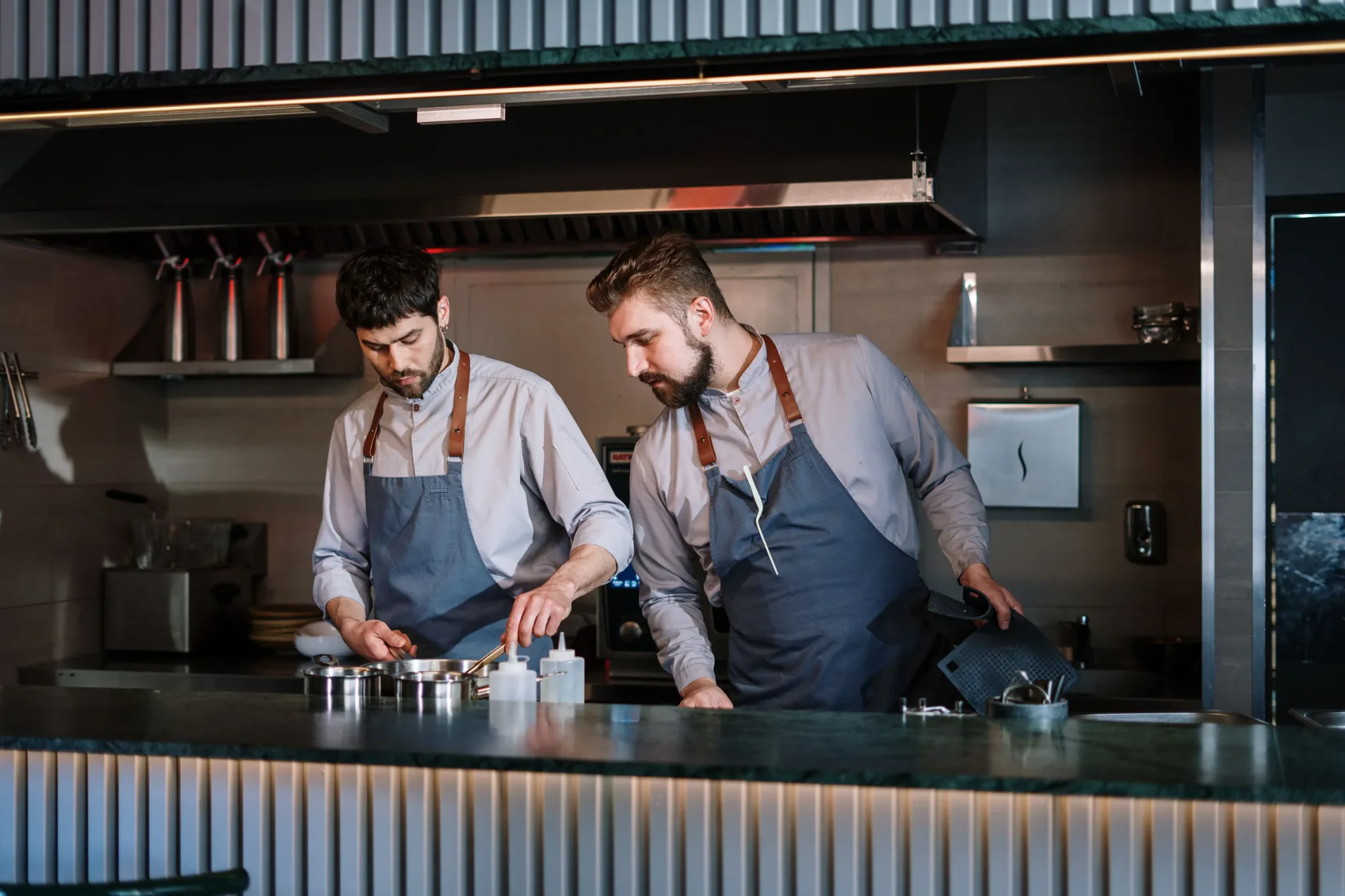 Twee koks in schort aan het werk in een open restaurantkeuken