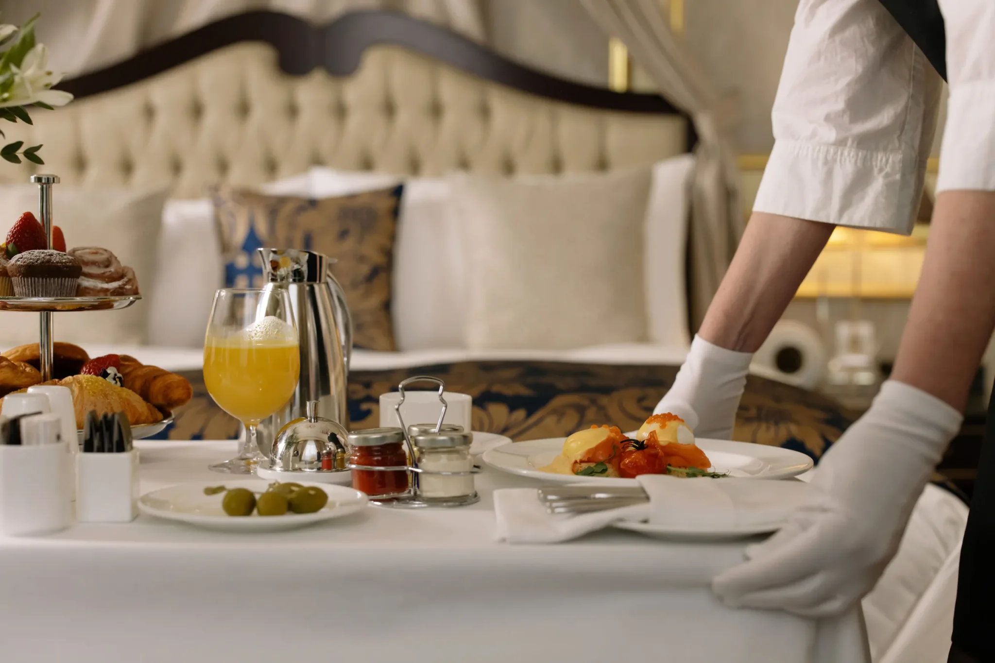 Medewerker zet een ontbijt met verse jus en croissants klaar op een hotelkamer