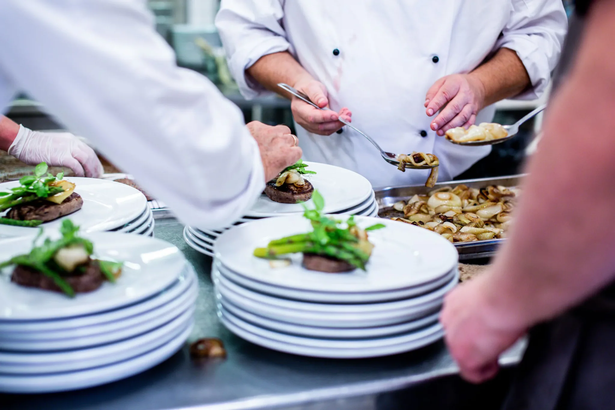 Koks werken borden af aan de pass, met stapels borden klaar voor de service