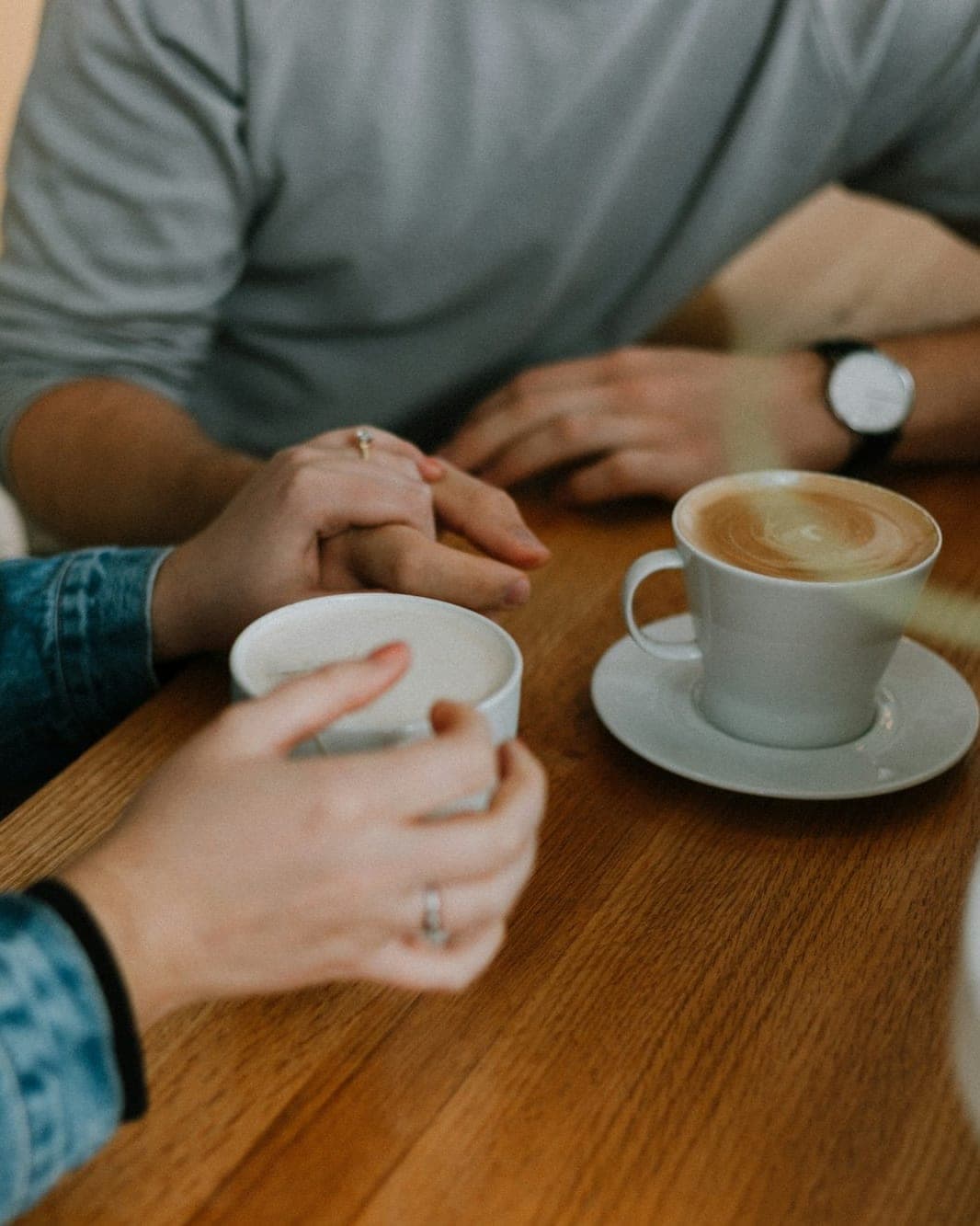 Twee mensen in gesprek aan een houten tafel, met een koffie tussen hen in