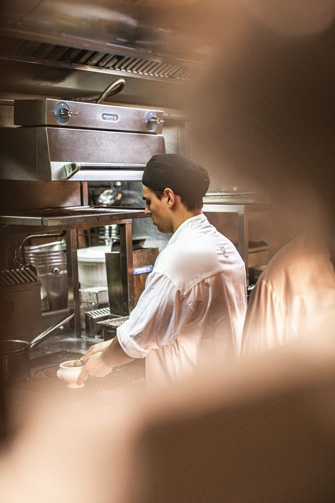 Een kok aan het werk in het warme licht van een restaurantkeuken