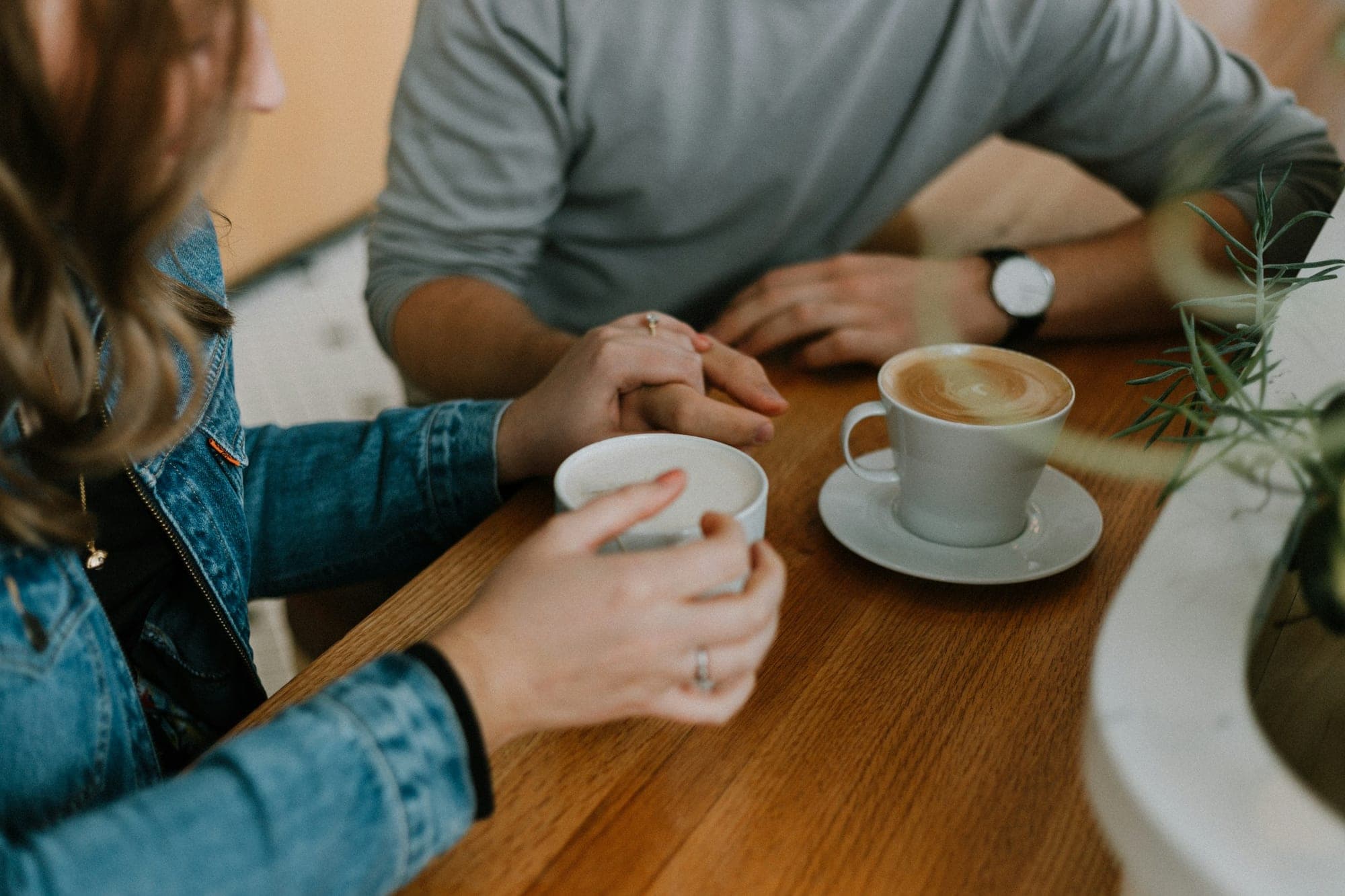 Twee mensen in gesprek aan een houten tafel, met een koffie tussen hen in